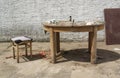 Broken old working table with a stool outside