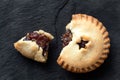 Broken open traditional british christmas mince pie with fruit filling isolated on black slate. Top view