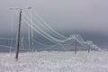 Broken phase electrical power lines with hoarfrost on the wooden electric poles on countryside in the winter after storm