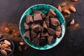 Broken pieces of dark chocolate in a vintage bowl and cocoa beans on a dark textured background, top view Royalty Free Stock Photo