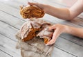 broken into pieces round fresh grain dark bread in hands of unrecognizable person on light wooden table  selective focus Royalty Free Stock Photo