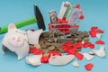Broken piggy bank, coins and hearts lying around, a supermarket cart with bills. Concept - buying a gift for loved ones