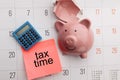 Broken piggy bank on a white calendar background, tax and savings concept Royalty Free Stock Photo