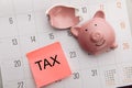 Broken piggy bank on a white calendar background, tax time concept Royalty Free Stock Photo