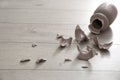 Broken pink ceramic vase on wooden floor