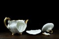 Broken porcelain teapot on a black background