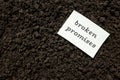Broken promises concept. Paper note in dark soil background.