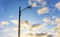 Broken public street lamp against cloudy blue skies with shiny daylight