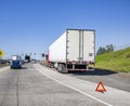 Broken red big rig semi truck with open hood and dry van semi trailer standing out of service on the highway road entrance Royalty Free Stock Photo