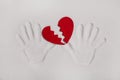 Broken red heart with hand prints in the sand for love sickness Royalty Free Stock Photo