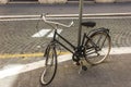 Broken retro bicycle with deflated and damaged wheel, enchained to the light pillar in the street of Rome Royalty Free Stock Photo