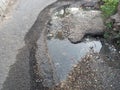 broken road with pothole filled with water