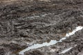 A broken rural country road after the rain. Puddles after rain on a dirt road. Clay, soil and puddles at cloudy day Royalty Free Stock Photo