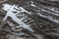 A broken rural country road after the rain. Puddles after rain on a dirt road. Clay, soil and puddles at cloudy day Royalty Free Stock Photo