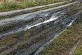 A broken rural country road after the rain. Puddles on a dirt road. Clay, soil and puddles at cloudy day light after Royalty Free Stock Photo