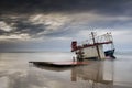 The broken ship along with the sea on a sandy beach and sunset t Royalty Free Stock Photo