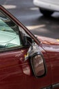 Broken side mirror hanging at a demolished car after car accident or vandalism injury and insurance loss due to hit and run shows Royalty Free Stock Photo