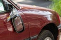 Broken side mirror hanging at a demolished car after car accident or vandalism injury and insurance loss due to hit and run shows Royalty Free Stock Photo