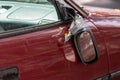 Broken side mirror hanging at a demolished car after car accident or vandalism injury and insurance loss due to hit and run shows Royalty Free Stock Photo