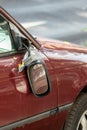 Broken side mirror hanging at a demolished car after car accident or vandalism injury and insurance loss due to hit and run shows Royalty Free Stock Photo