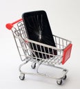 A broken smartphone in a shopping trolley. The concept. Defective goods