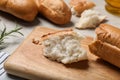 Broken tasty baguette on white wooden table, closeup