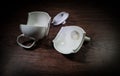 broken teapot on a dark toned foggy background. Pieces of ceramic teapot on wooden table