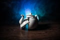 broken teapot on a dark toned foggy background. Pieces of ceramic teapot on wooden table