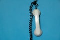 broken telephone receiver on wire weighs on blue isolated background, telephone receiver on prododi is broken Royalty Free Stock Photo
