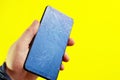A broken touch phone with a cracked screen in your hand on a yellow background. Royalty Free Stock Photo