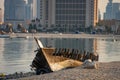 Broken Traditional fishing boat At beach near calm blue water with cityscape of doha on background