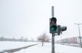 Broken and out of use traffic light on the urban street cross walk for pedestrians in the city damaged by snow in the winter time Royalty Free Stock Photo