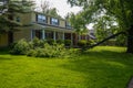 A broken tree limb lays across the green lawn in front of a large house after a severe storm Royalty Free Stock Photo