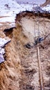 Broken underground water pipe in big deep hole with grey asphalt under thin snow carpetfd Royalty Free Stock Photo