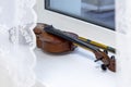 A broken violin lies on a white windowsill.