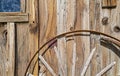 A broken wagon wheel leans on the wall of an rustic wooden shack Royalty Free Stock Photo
