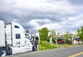 Broken white big rig semi truck tractor with open hood standing on the road shoulder out of service