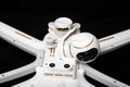 Broken white drone after a fall. Isolated on a black background. Damaged stabilizer camera gimbal. Plugged cable loop Close up.