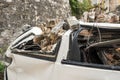 Broken white vehicle buried with old gray bricks from shattered wall. Insurance concept.