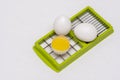 Broken and whole white eggs on green kitchen cutter on a white surface Royalty Free Stock Photo