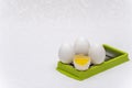 Broken and whole white eggs on green kitchen cutter on a white surface Royalty Free Stock Photo
