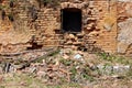 Broken window mounted on red brick wall of ruins of destroyed old wooden and bricks suburban family house mixed with small plants Royalty Free Stock Photo