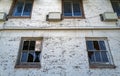 Broken windows and air conditioners on a white brick wall of an abandoned hotel Royalty Free Stock Photo