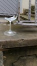 Broken wine glass standing on ancient partly broken stone pedestal,against background of stairs and iron curved railing