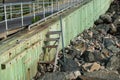 Broken wooden steps from a rocky beach to a boardwalk up a sea wall Royalty Free Stock Photo