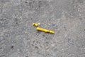 Broken yellow crayon, lying on a dirty gray concrete street