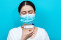 Bronchial asthma. Blurry portrait of a woman in a medical mask holding an inhaler in front of her and looking it. Blue Royalty Free Stock Photo