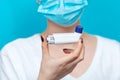 Bronchial asthma. A female doctor in a medical mask, holding an inhaler in front of her. The hand with the medicine close-up. Blue