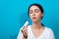 Bronchial asthma. Portrait of a young woman holding inhaler. Blue background. Copy space Royalty Free Stock Photo