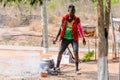 Unidentified Ghanaian man in colored clothes cooks on fire.